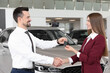 © New Africa - Salesman giving key to client near new car in salon