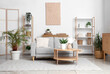 © Pixel-Shot - Interior of light living room with grey sofa, shelf units and plants