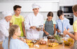 © JackF - Young guy and adult woman cook in uniform teaches group of children how to cook dish