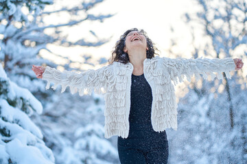 Wall Mural - A woman happily playing with snow in a snow-covered winter forest