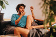 © qunica.com - A young person lounges on a cozy couch, sharing snacks and laughter with a friend. The scene captures a moment of relaxation and camaraderie in a comfortable home setting.