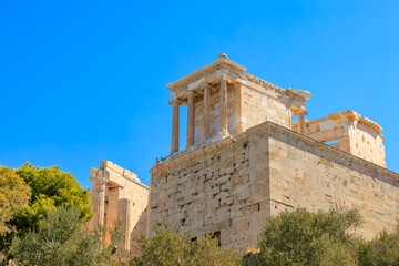 Wall Mural - A large building with a stone facade and a green tree in front of it, the Acropolis of Athens