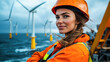 © kongkiat chairat - female offshore wind turbine technician stands confidently by sea, wearing orange safety helmet and jacket. wind turbines in background highlight her role in renewable energy