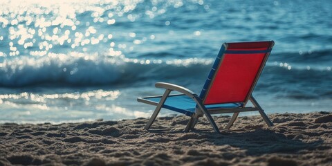 Poster - A red and blue beach chair by the sea, on the shore.