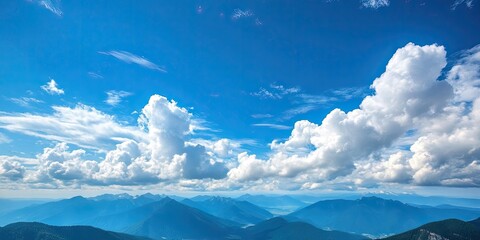 Poster - Dramatic landscape - white clouds above the mountain peaks in a blue sky on a sunny day with a copyspace available.