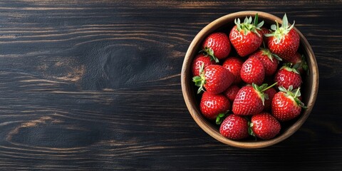Poster - Bowl filled with fresh strawberries on a dark wooden table with copyspace. Top view.