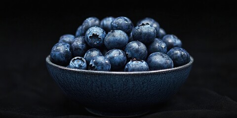 Poster - Fresh, juicy blueberries in a bowl against a black background. Low key photography.
