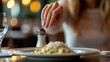 © Sinechana - 98.A close-up of a woman's hand gently pushing away a salt and pepper shaker placed in front of her at a restaurant. The gesture is calm but definitive, with her focus on the plate of food in front