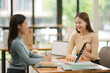 © aekachai - Two Asian businesswomen working with documents in an office.