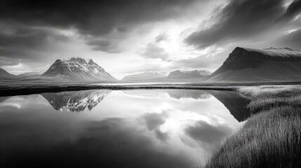 Monochrome landscape reflecting serene mountains and clouds in calm water, showcasing a peaceful black and white photography exhibit.