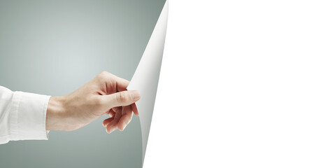 Poster - A hand holding and peeling back a blank sheet of paper, revealing empty white space. Set against a soft gradient background. Concept for mockup template