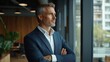 © Chandlerlikes - Happy confident mature 45-year-old business man investor standing in office looking away. Middle-aged rich business owner male CEO executive leader wearing suit at work thinking on future success