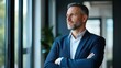 © Chandlerlikes - Happy confident mature 45-year-old business man investor standing in office looking away. Middle-aged rich business owner male CEO executive leader wearing suit at work thinking on future success