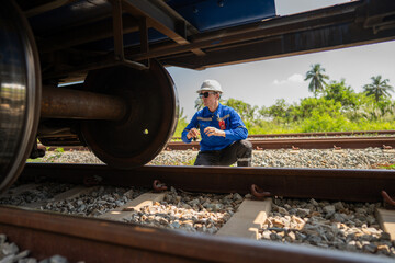 Wall Mural - Male Engineer railway under checking construction process oil cargo train and checking railway work on railroad station.