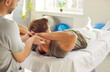 © Studio Romantic - Male physiotherapist helping patient lying on couch to do exercises during rehabilitation and therapy session. Osteopath or massage therapist providing support in neck shoulder massage in rehab clinic
