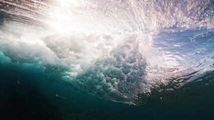 Wall Mural - Ocean wave breaks over the reef bottom. Underwater view of a surfing spot in the Maldives