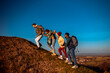 © Zoran Zeremski - Smiling group of friends having fun while hiking together up to the hill at sunset.