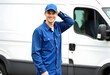 © StockLab - Delivery man or a driver standing in his blue uniform and blue cap, standing next to a blue van