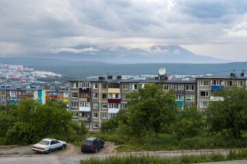 Wall Mural - Evening urban landscape. Top view of the buildings and streets of the city. Cars are parked on the side of the road. Volcanoes in the distance. Petropavlovsk-Kamchatsky, Kamchatka, Far East of Russia.