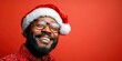 © Anastasiia K. - joyful handsome black man in santa claus hat isolated on bright red background, copy space. man in new year christmas hat