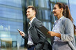 © muse studio - Professionals Walking With Smartphones and Tablets Near a Modern Office Building in the City