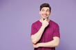 © ViDi Studio - Young Caucasian man he wear violet t-shirt casual clothes put hand prop up on chin, lost in thought and conjectures isolated on plain pastel light purple background studio portrait. Lifestyle concept.
