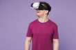 © ViDi Studio - Young smiling happy cheerful Caucasian man he wear violet t-shirt casual clothes watching in vr headset pc gadget isolated on plain pastel light purple background studio portrait. Lifestyle concept.