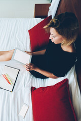 Wall Mural - top view of female blogger holding portable pc with blank screen resting on bed, young woman making 