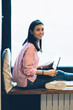 © BullRun - Full length portrait of gorgeous cheerful brunette student waiting for useful application installation on modern netbook during sitting against window with advertising area for promotional content