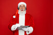 © InsideCreativeHouse - Shocked mature Santa Claus with real beard in red hat headset holding pen and clipboard, isolated on red background. Senior man planning his day, work and holiday celebration.