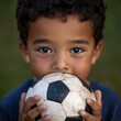 © Mandeep - young child holding a soccer ball with a focused expression