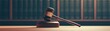 © Chanoknan - A gavel rests on a wooden block in front of a backdrop of law books, symbolizing justice and legal authority.