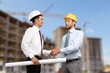 © BillionPhotos.com - construction worker with contractor shaking hands in renovation site.