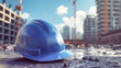 © Anoo - Blue construction hard hat resting on the ground amid a bustling building site surrounded by cranes and under construction structures during daylight