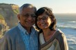 © Markus Schröder - Portrait of a satisfied indian couple in their 50s wearing a chic cardigan in front of dramatic coastal cliff background