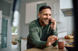 © Drazen - Happy man making phone call while having  cup of coffee in  kitchen.