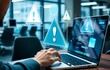 © jamal - Person typing on a laptop with holographic warning symbols on screen in an office environment, concept of cybersecurity threat