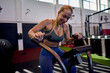 © DusanJelicic - Young woman intensely using a stationary bike in a cross fit gym, focused on maintaining her fitness regimen.
