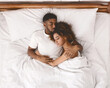 © Prostock-studio - Young african-american couple sleeping together in bed, top view, copy space