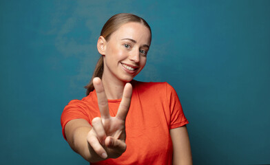 Wall Mural - smiling and looking happy, carefree and positive, gesturing victory or peace with one hand