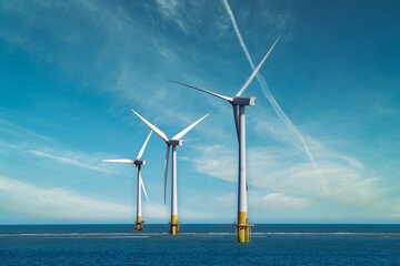 Three offshore wind turbines standing in the sea, with clear blue sky. Wind Turbines at Sea. Sustainable energy production. Green Energy, clean power, clean energy concept.