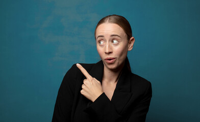 Wall Mural - feeling joyful and surprised, smiling with a shocked expression and pointing to the side