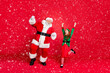 © deagreez - Full body photo of excited santa claus elf in hat headwear with redhead white haircut raise fists scream yes celebrate party wear green costume isolated over red background