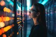 © Tanu - Young woman wearing futuristic glasses examines data servers in a modern data center under vibrant LED lights at night