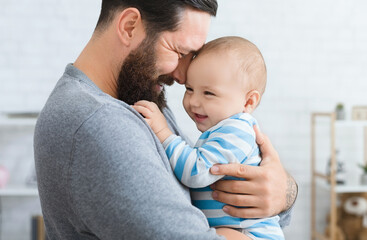 family love and joy. happy father embracing with his laughing adorable baby