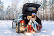 © maxbelchenko - Selfie time. Young Woman sitting in the trunk of her car and taking selfie on a background of snow-covered winter forest. Holidays, rest, blogging.