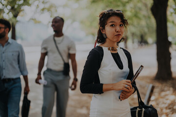 Wall Mural - A group of young people casually stroll through a lush park, exuding confidence and casual elegance. The scene captures the essence of modern work-life balance and urban outdoor interaction.