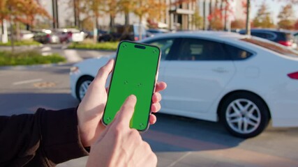Man holds smartphone using car sharing app against auto