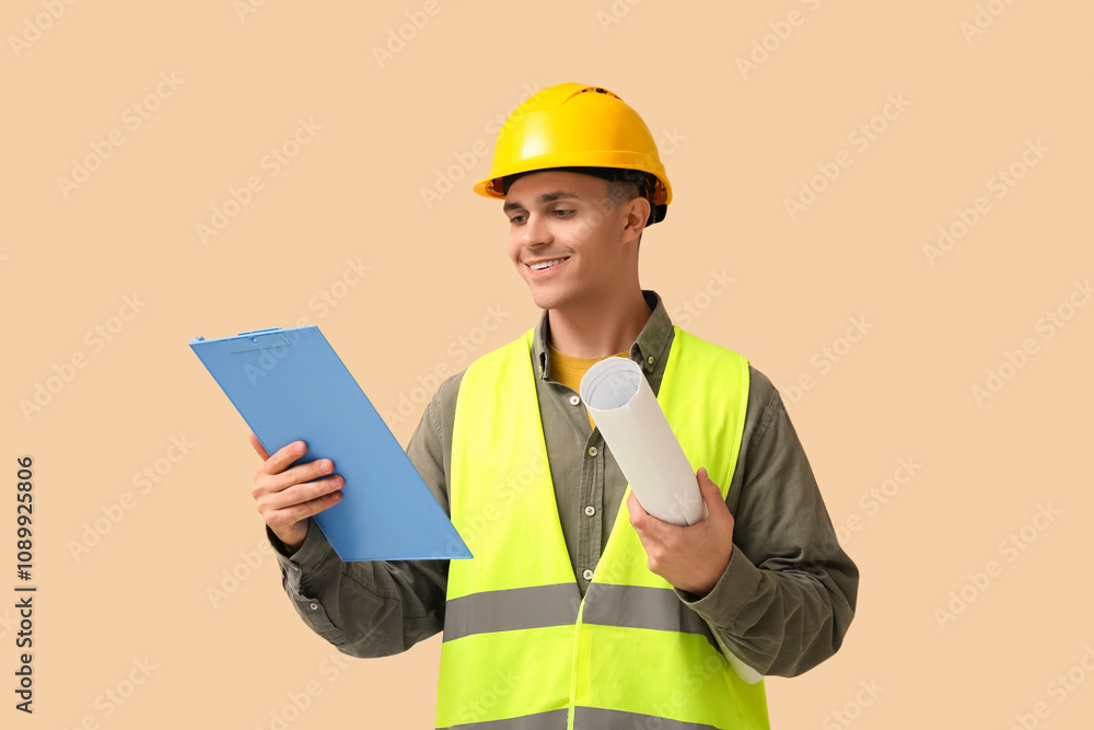 Young male engineer with clipboard and blueprint on beige background