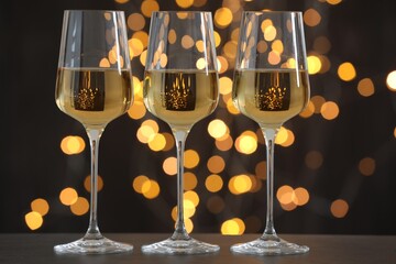 Canvas Print - Glasses of luxury white wine on wooden table against dark background with blurred lights. Bokeh effect